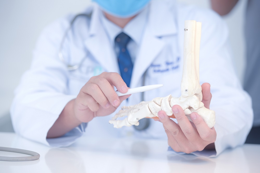 A doctor holding a foot model while discussing Platelet-Rich Plasma (PRP) therapy